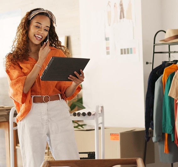 Happy young start up business owner talks to her Jade Finance broker on the phone while reading calculated estimates online.