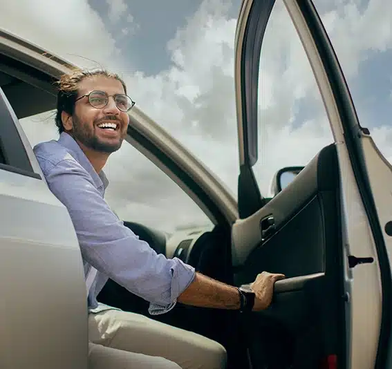 young middle-eastern man going out the car door and smiling