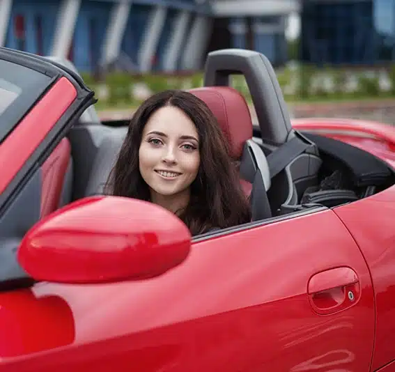 brunette woman driving luxury red car