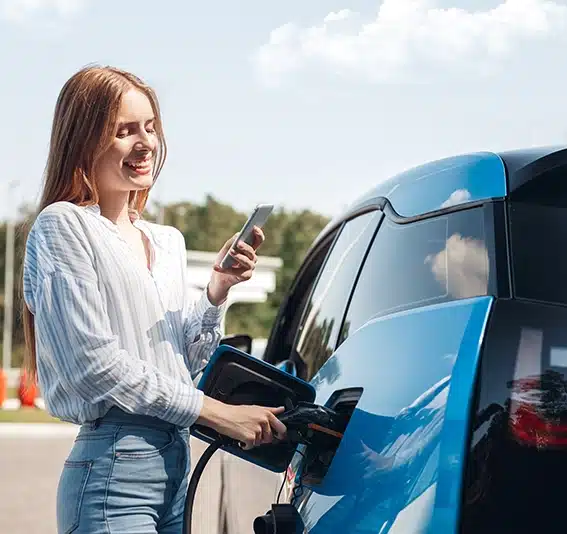 Woman traveling by electric car having stop at charging station