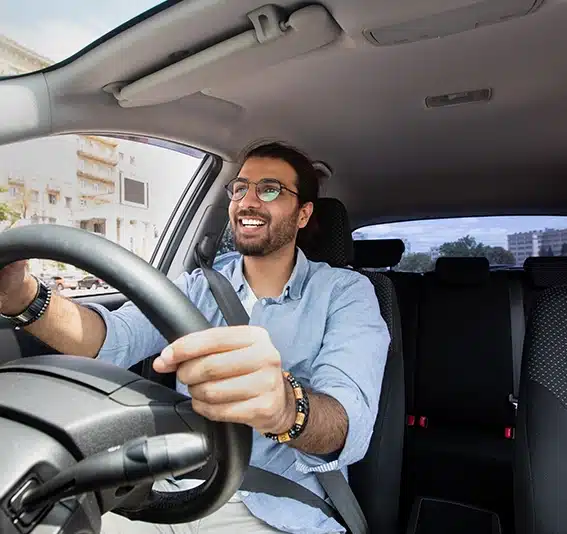 Middle-eastern guy in casual attire and glasses driving car, captured from dashboard perspective