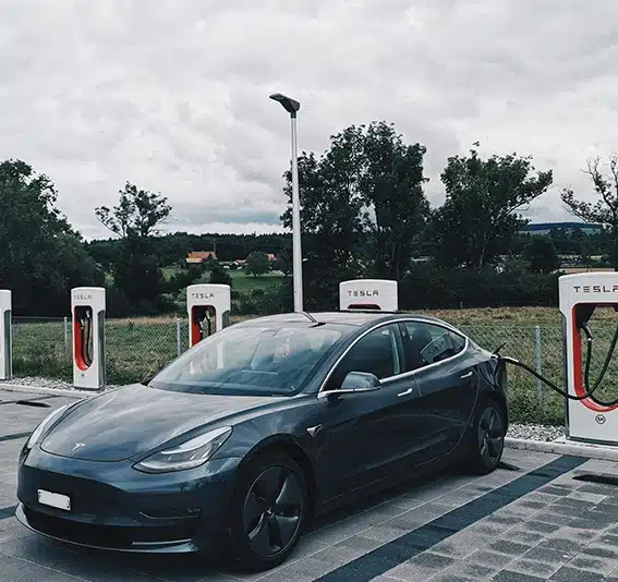 Black Tesla car charging at Tesla charging station
