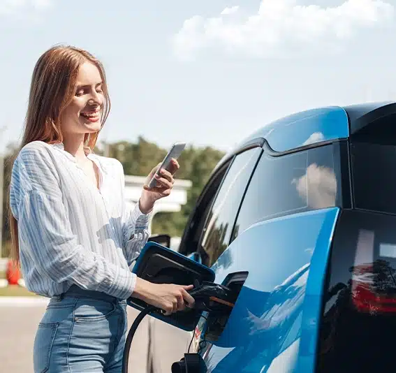 Woman traveling by electric car having stop at charging station