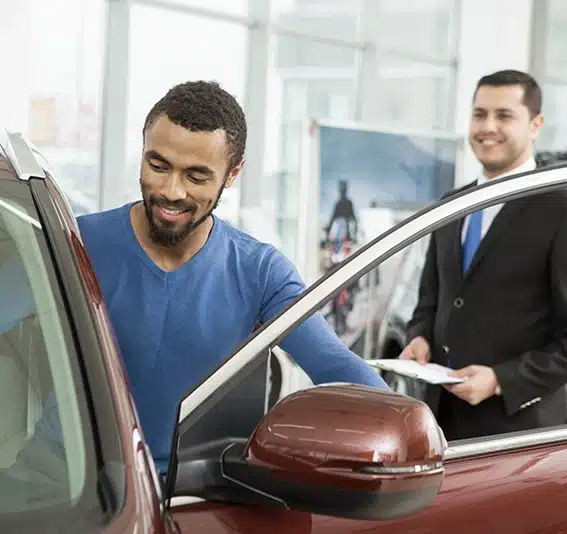 young man smiling getting inside new car at the dealership