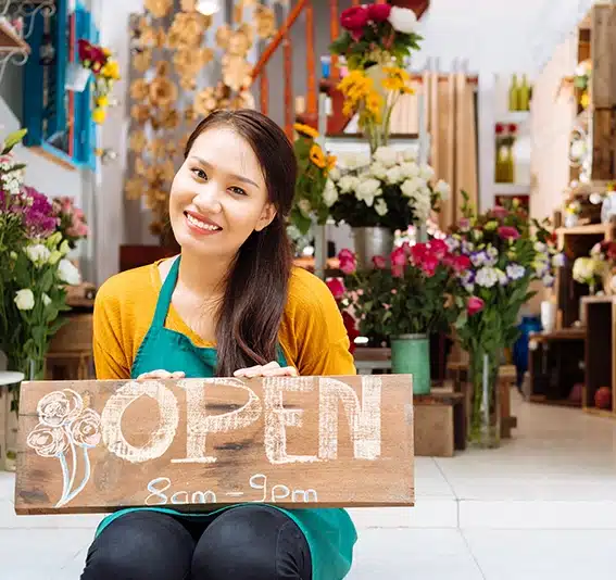 Pretty seller of the shop sitting with Open sign