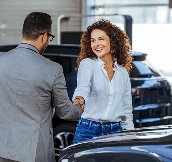 Salesman congratulating his female customer for buying a new car in a showroom