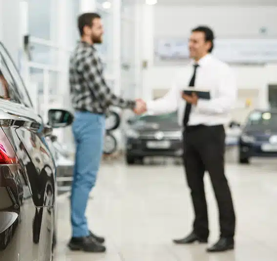 Two man shaking hands in a car showroom