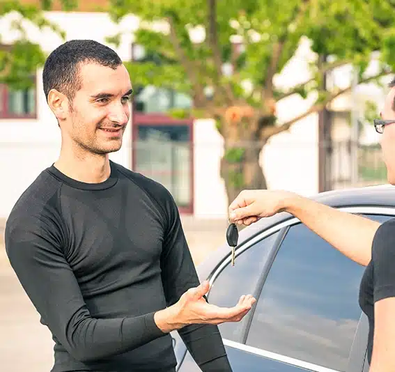 Man receiving car keys after second-hand car sale