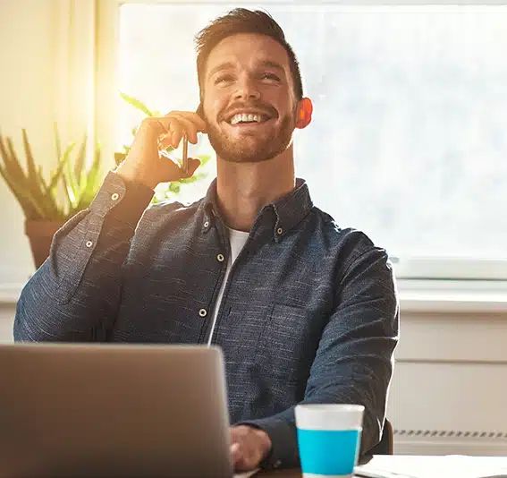 A businessman chatting on a mobile phone while working at his desk looking up into the air