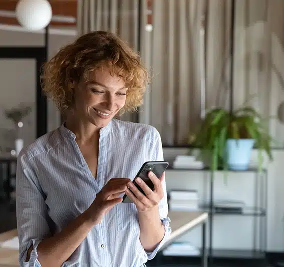 A young woman is using her cellphone alone in the office