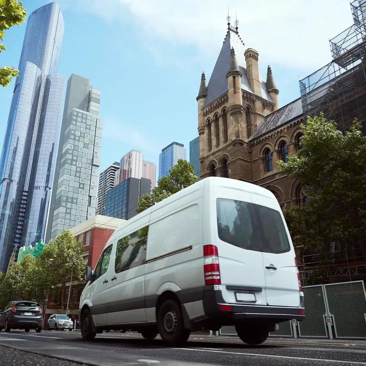 White commercial van driving in a city