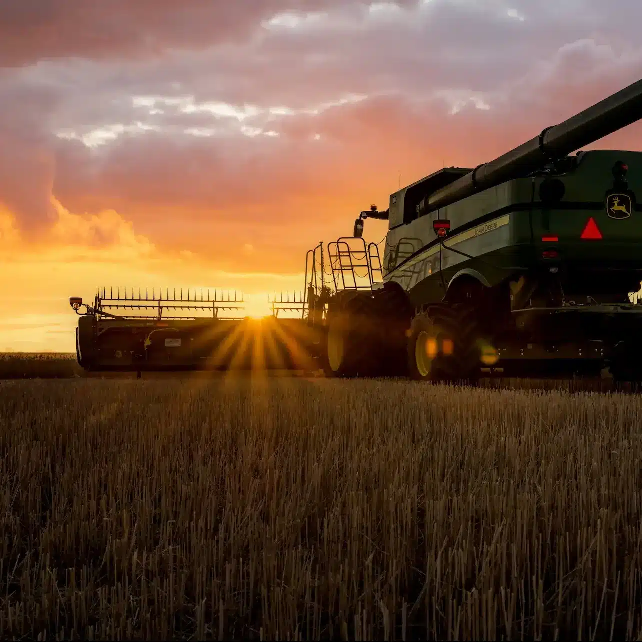 A combine harvester working in the field at sunset