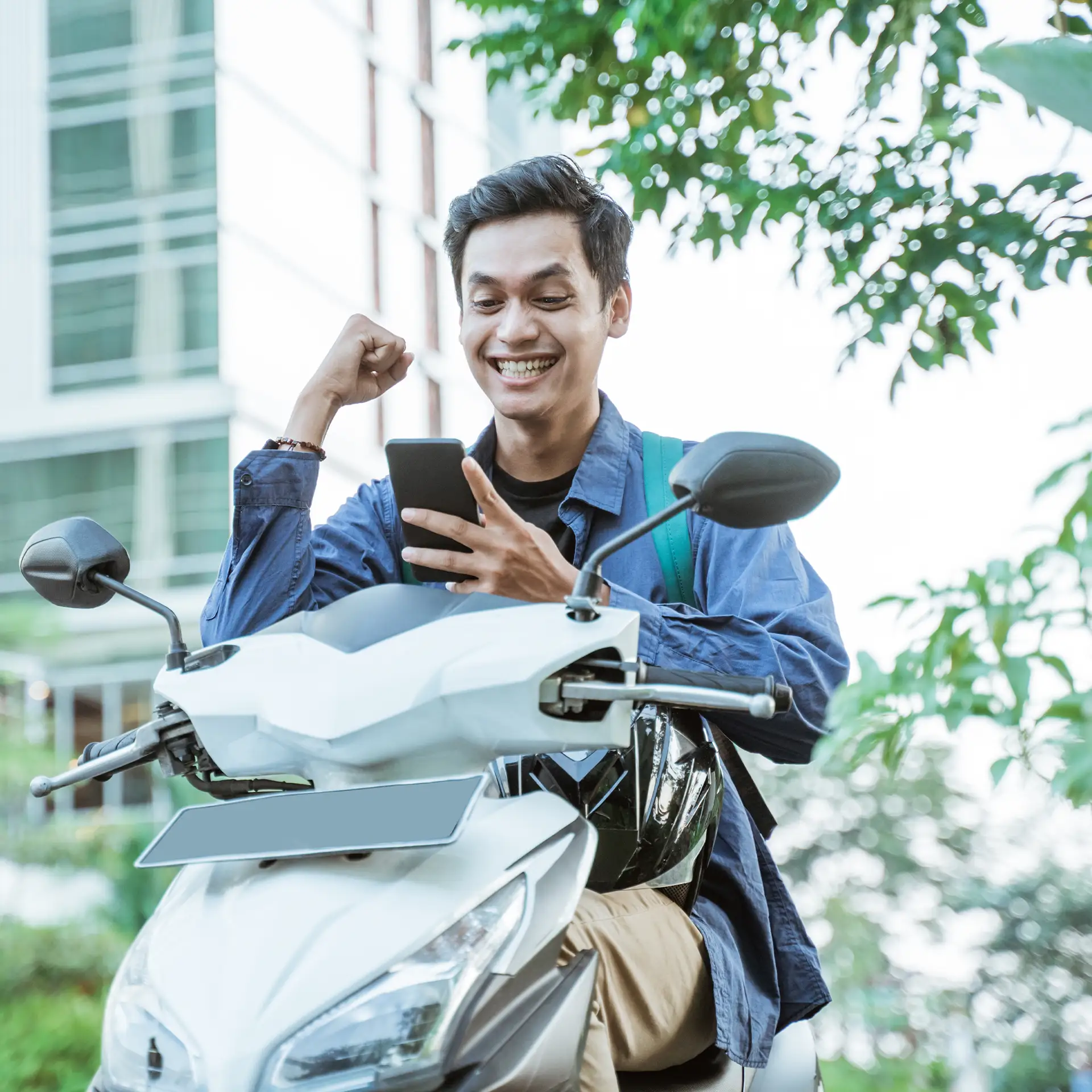 Excited asian man using a cellphone while riding a motorcycle