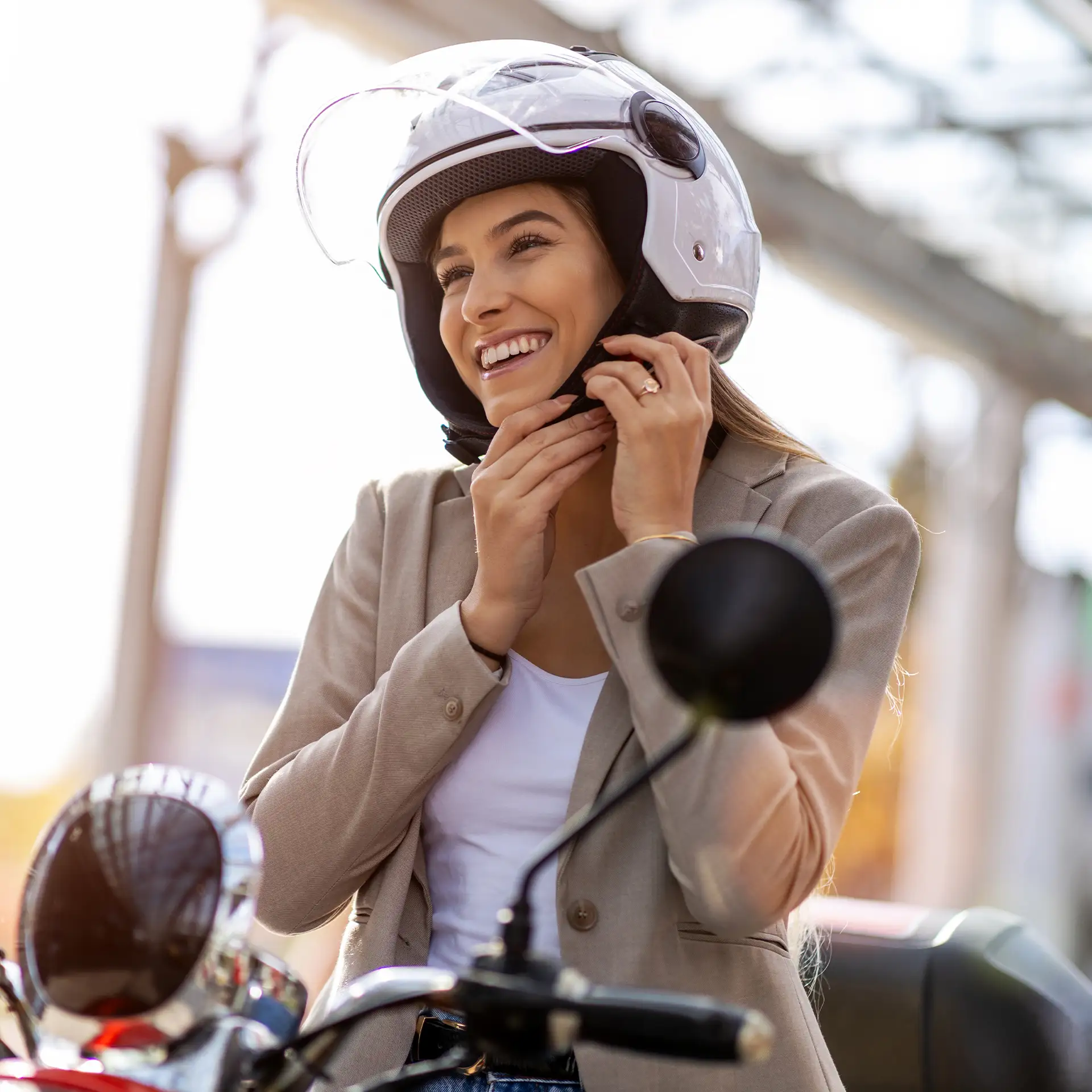 A woman on a scooter tightens helmet