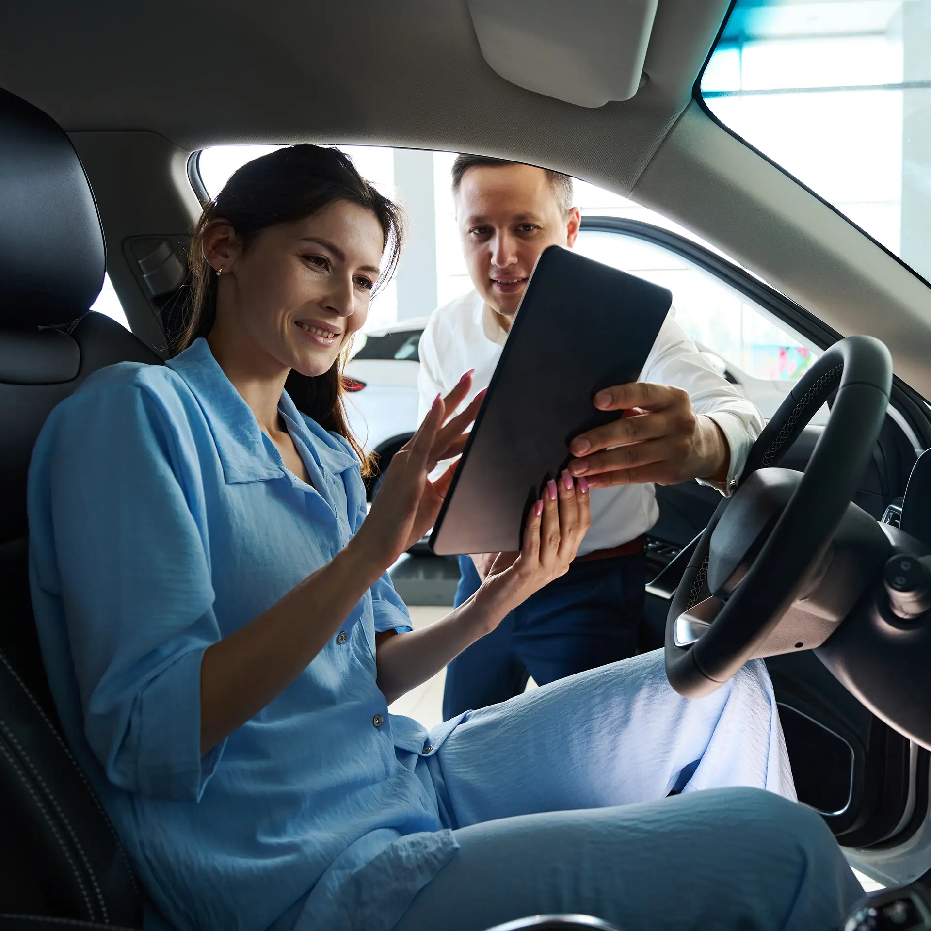 Car dealership manager presents new car documents to customer