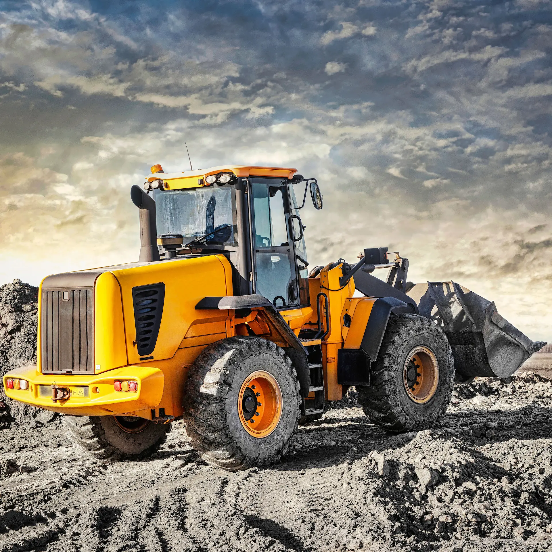 A big wheeled loader driving across freshly moved soil on an earthworks site.