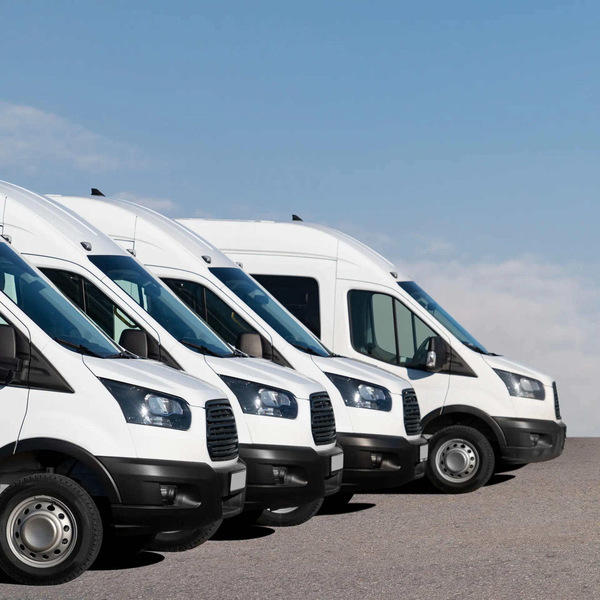 A row of commercial vans lined up parked at a fleet depot.
