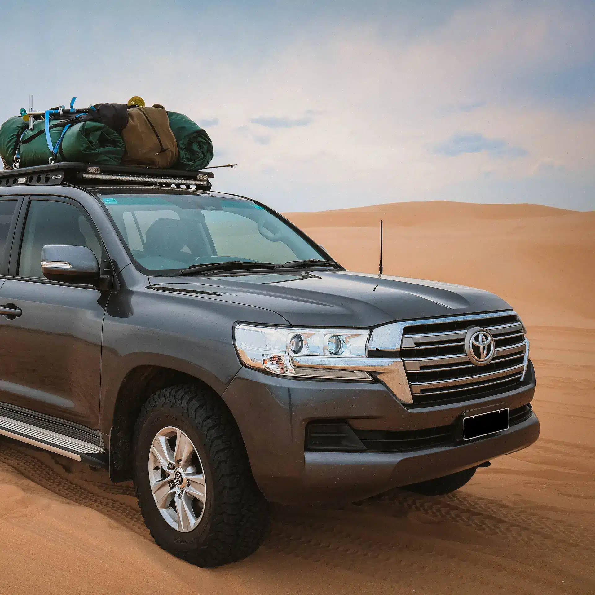 A Toyota Landcruiser parked on sandy dunes of the desert.