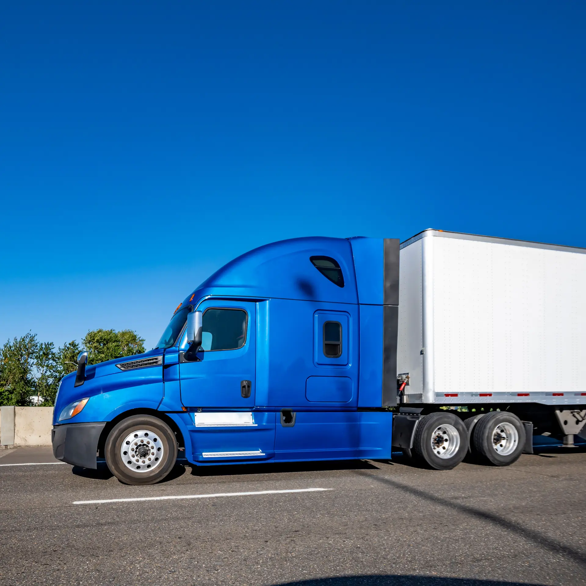 Industrial carrier blue big rig semi truck tractor with extended cab for truck driver rest transporting cargo in dry van semi trailer running on the multiline highway road on a sunny day