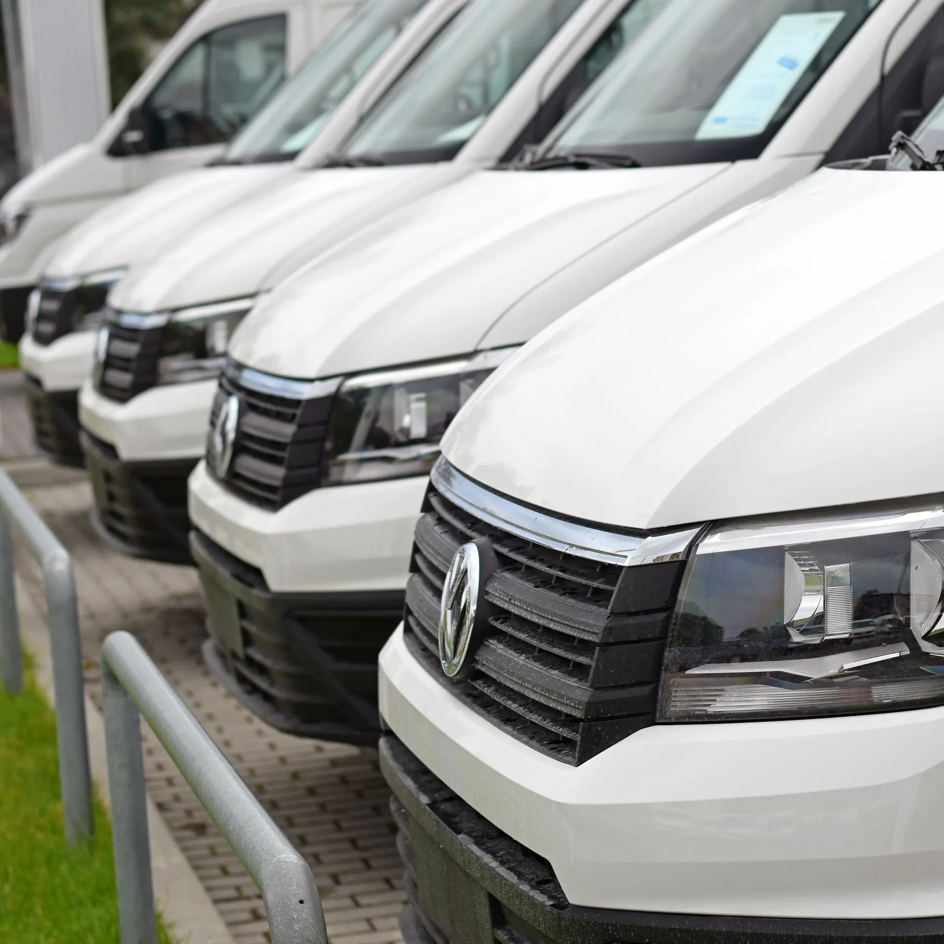 A row of white VW light commercial vans in a fleet parked at a depot