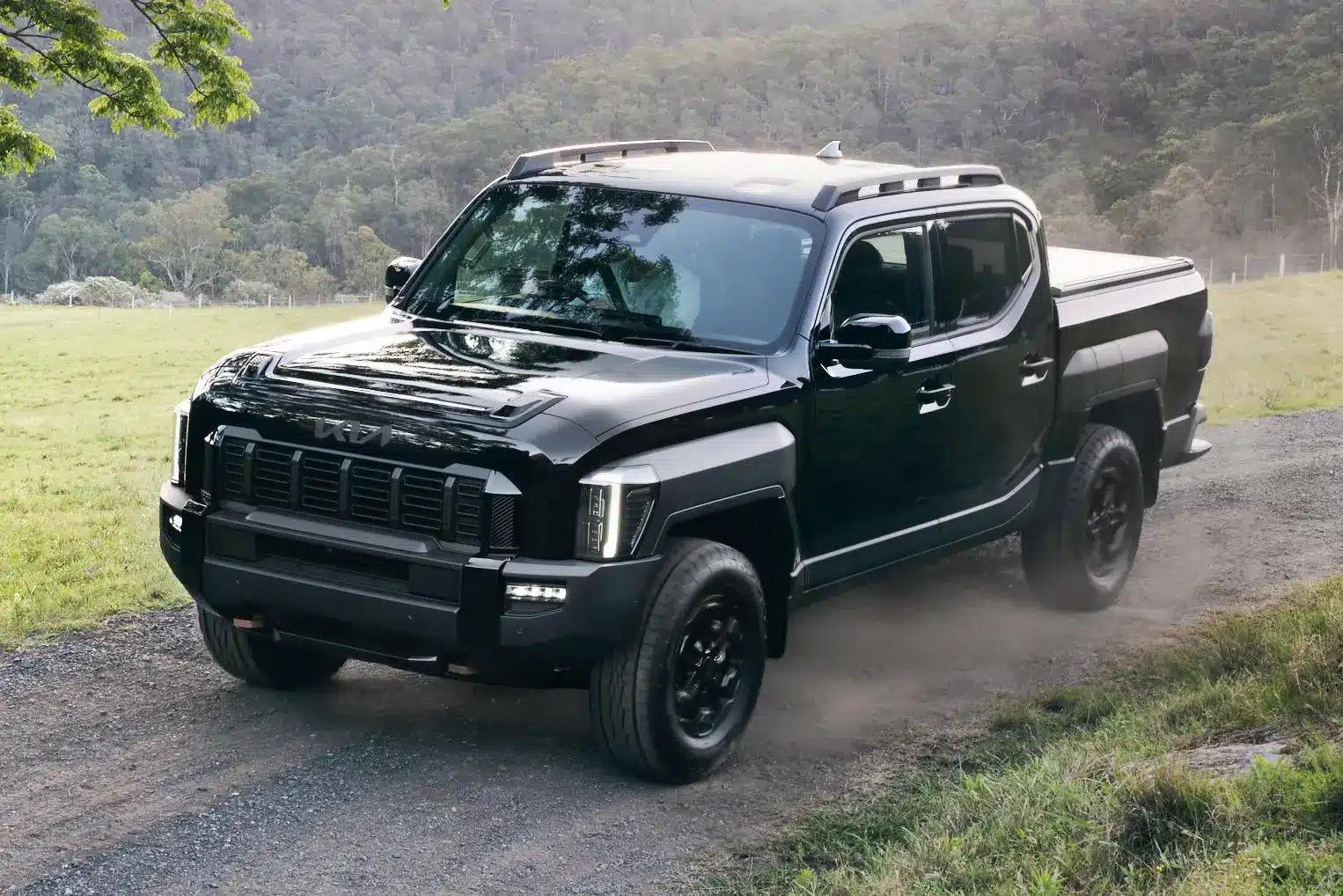 Black Kia Tasman driving along a country dirt road