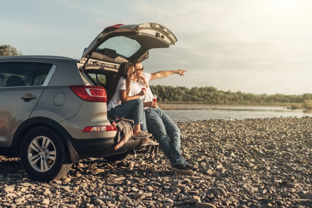 Happy Couple on Roadtrip into the Sunset in SUV Car